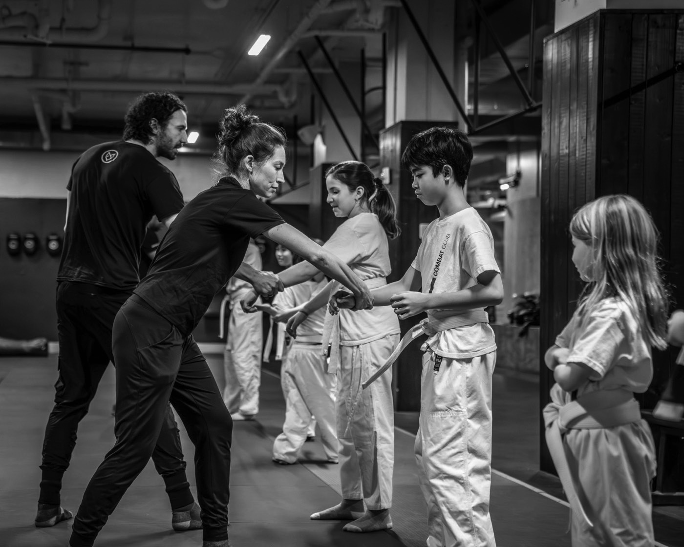 Combat Club instructor adjusting a young student's grip in class